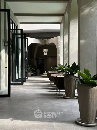 Luxurious modern building entrance with elegant arches and stylish outdoor seating.