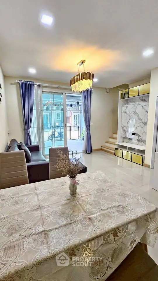 Elegant living room with modern decor, featuring a stylish chandelier and large windows for natural light.
