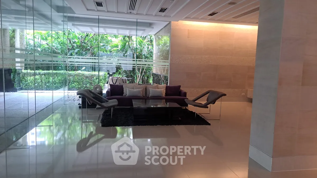 Luxurious modern living room with glass walls and garden view, featuring elegant furniture and stylish decor.