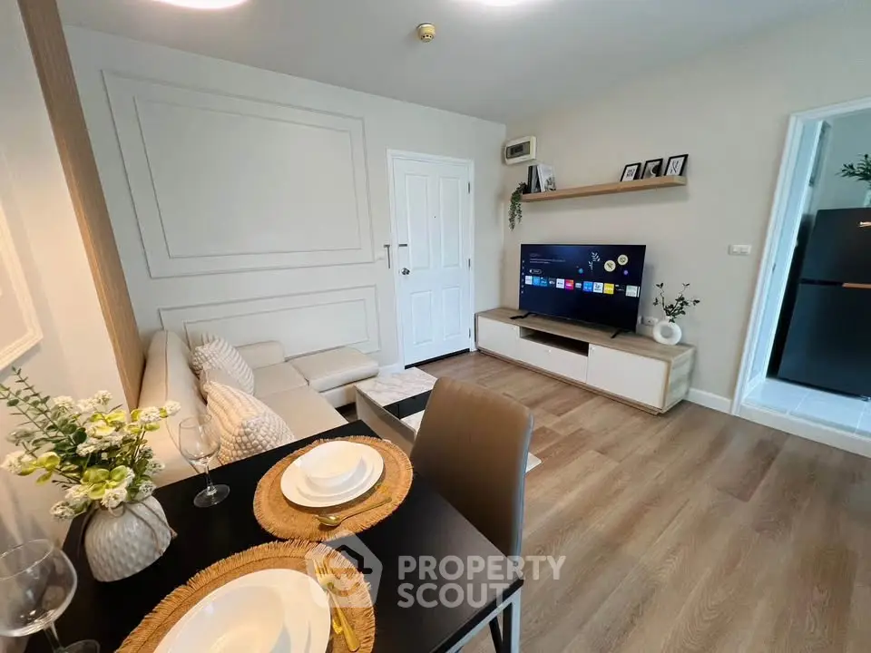 Modern living room with stylish decor and open layout, featuring a cozy sofa and flat-screen TV.