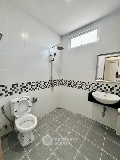 Modern bathroom with sleek tiles and contemporary fixtures, featuring a shower and toilet.