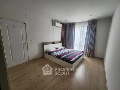 Spacious bedroom with modern decor and large window for natural light.