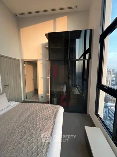 Modern bedroom with large windows and city view, featuring sleek design and ample natural light.