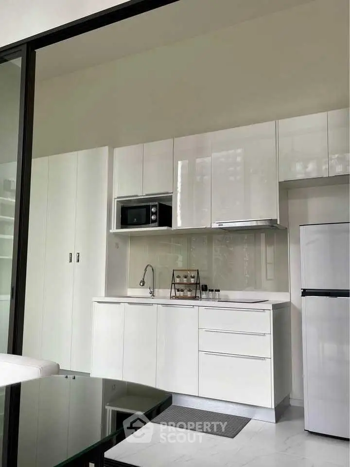 Modern kitchen with sleek white cabinets and built-in appliances.