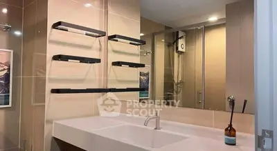 Modern bathroom with sleek fixtures and large mirror, featuring a stylish towel rack and elegant sink design.