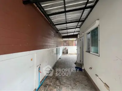 Covered outdoor area with tiled flooring and metal roof, ideal for utility or storage use.
