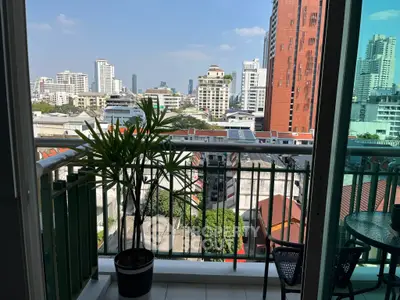 Stunning city view from a modern balcony with potted plant and seating area.