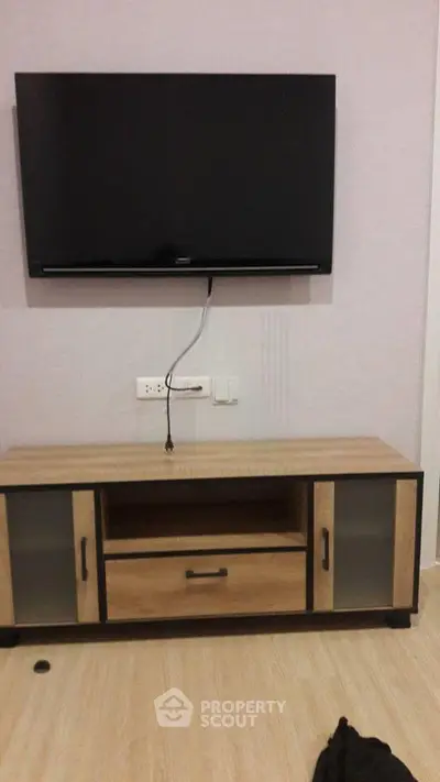 Modern living room with wall-mounted TV and stylish wooden cabinet.