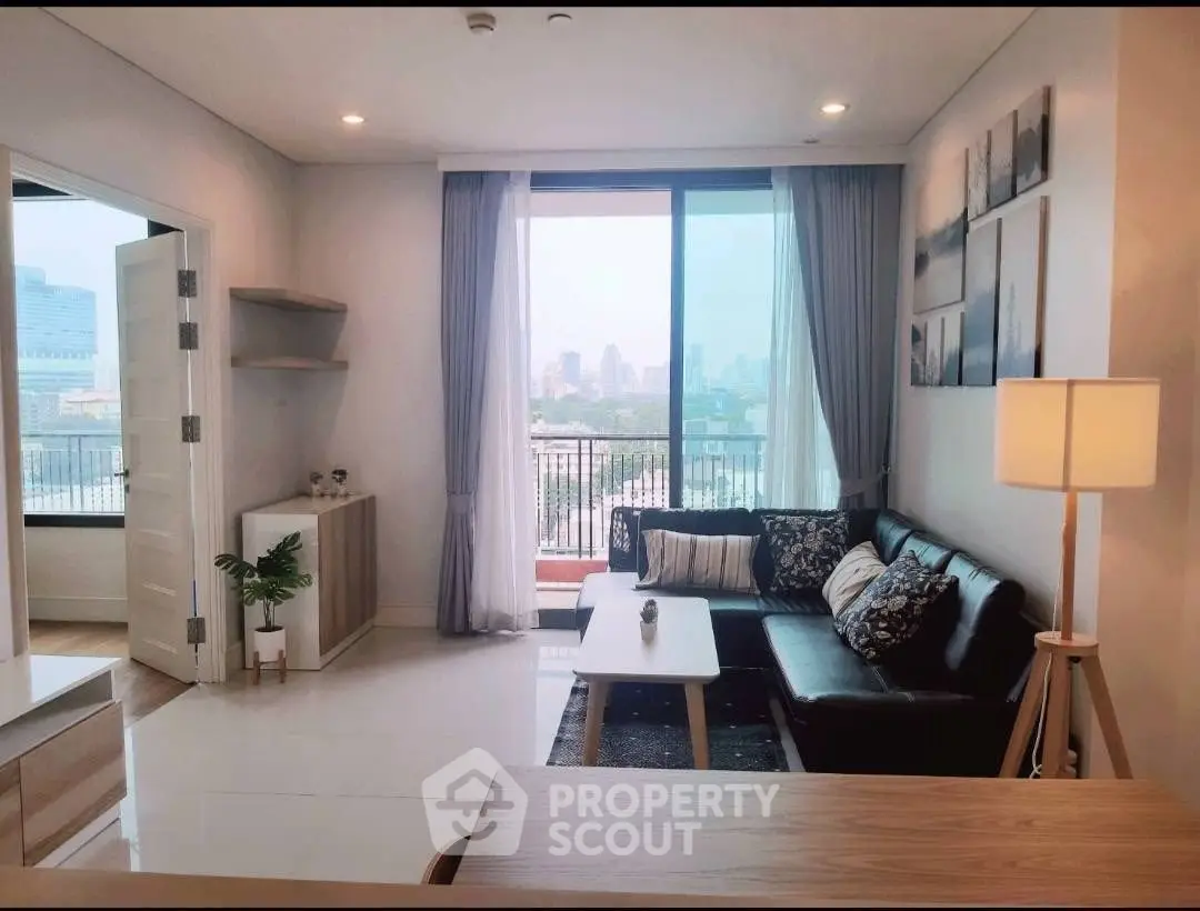 Modern living room with city view, stylish decor, and ample natural light in a high-rise apartment.