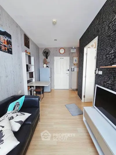 Modern living room with stylish decor and compact layout, featuring a black sofa and wall-mounted TV.