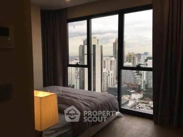 Luxurious bedroom with stunning city view from floor-to-ceiling windows in high-rise apartment.