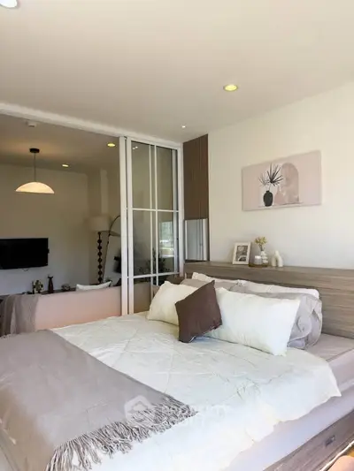 Modern bedroom with stylish decor and sliding glass doors leading to a cozy living area.