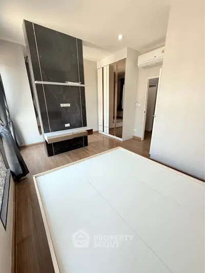 Modern bedroom with sleek design and ample natural light, featuring mirrored wardrobe and air conditioning.