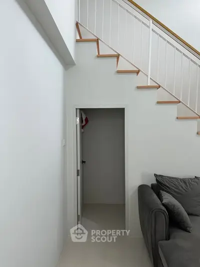 Modern interior with staircase and cozy gray sofa in a minimalist living space.