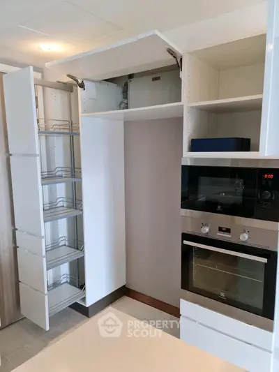 Modern kitchen with sleek cabinets and built-in oven, showcasing efficient storage solutions.