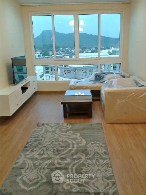 Spacious living room with large window offering stunning city and mountain views.