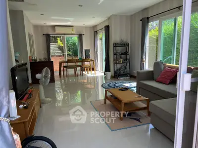 Spacious living room with modern decor and large windows offering garden views.