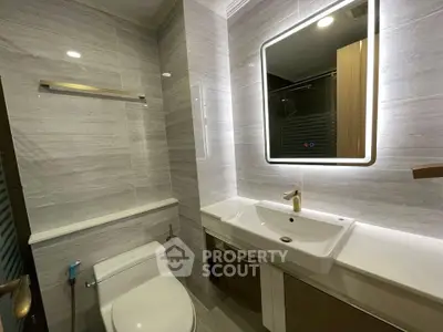 Modern bathroom with sleek fixtures and illuminated mirror in a contemporary apartment.