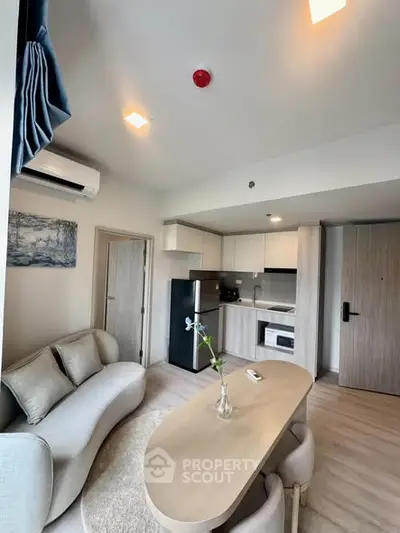 Modern living room with open kitchen, featuring sleek furniture and contemporary design.
