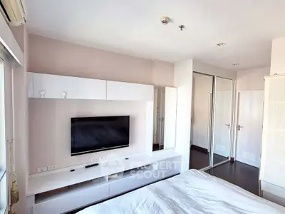 Modern bedroom with sleek white furniture and wall-mounted TV