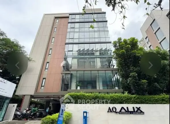 Modern residential building with glass facade and lush greenery at AQ Alix Residence.