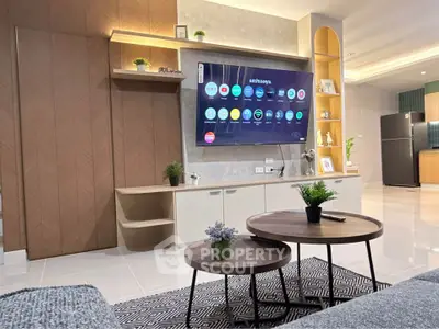 Modern living room with smart TV, stylish furniture, and open kitchen layout in a contemporary apartment.