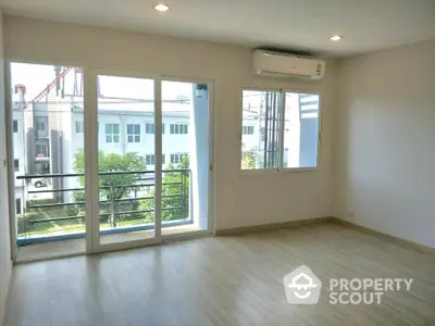 Spacious, well-lit living room with large sliding glass doors leading to a balcony, offering a blend of comfort and natural light.