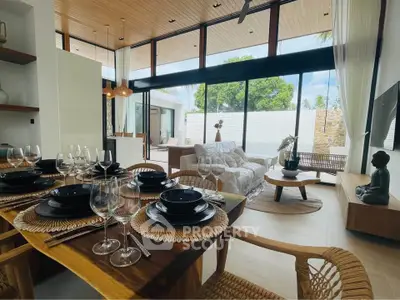 Luxurious open-plan living room with elegant dining area and expansive glass doors leading to a serene outdoor space.
