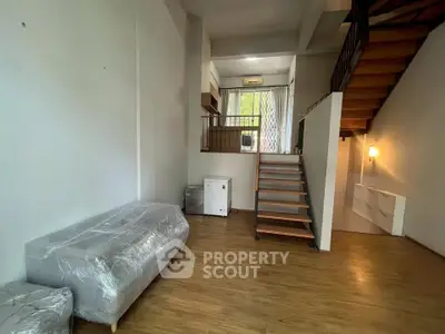 Modern loft-style living room with wooden staircase and natural light