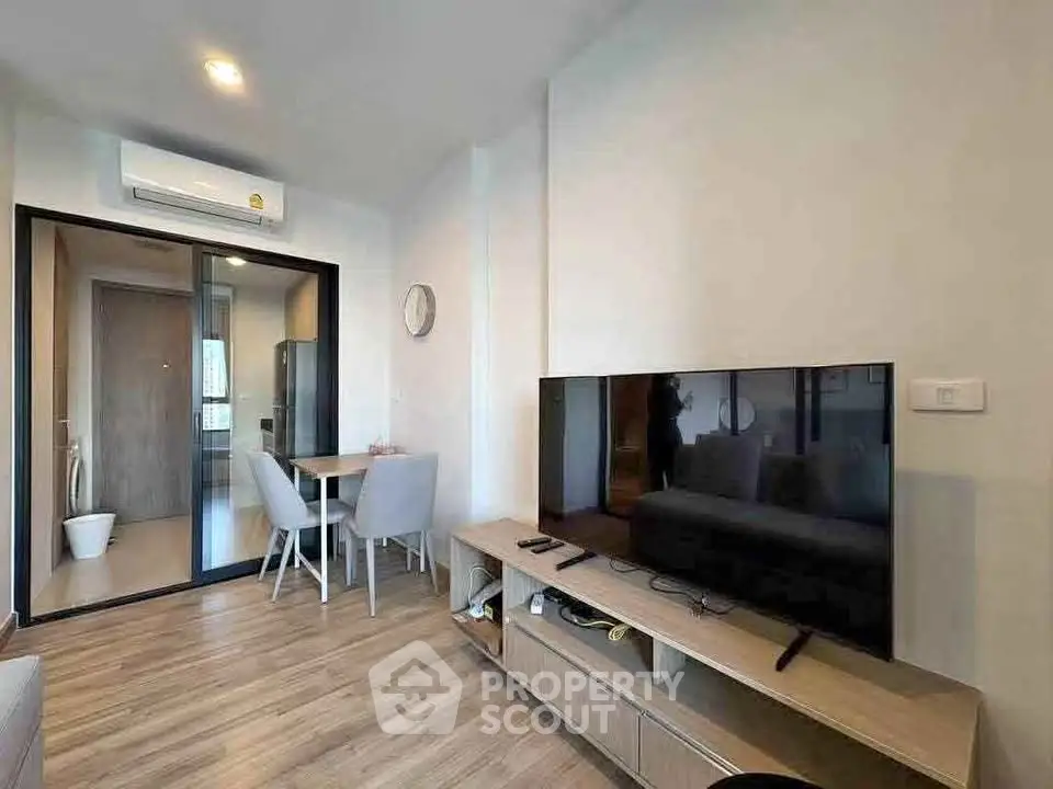 Modern living room with sleek TV setup and dining area in stylish apartment.