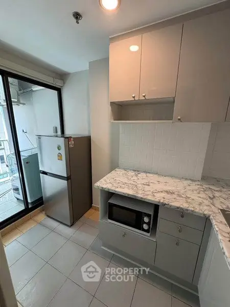 Modern kitchen with marble countertops and stainless steel appliances in a bright apartment.