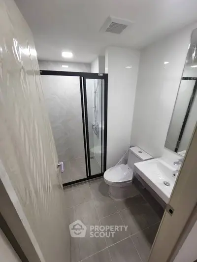Modern bathroom with glass shower and sleek fixtures in contemporary apartment.