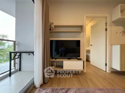 Modern living room with balcony access and sleek TV setup, featuring wooden flooring and neutral decor.