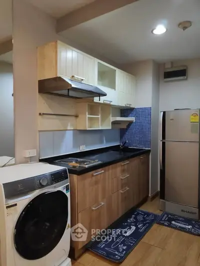 Modern kitchen with washing machine and fridge, sleek cabinetry, and stylish backsplash.