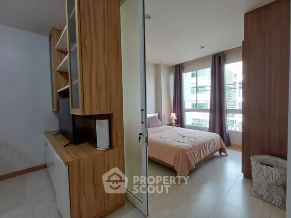Modern bedroom with wooden accents and large windows in a stylish apartment.