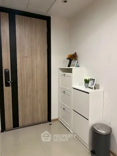 Modern apartment entrance with sleek wooden door and stylish white storage cabinets.