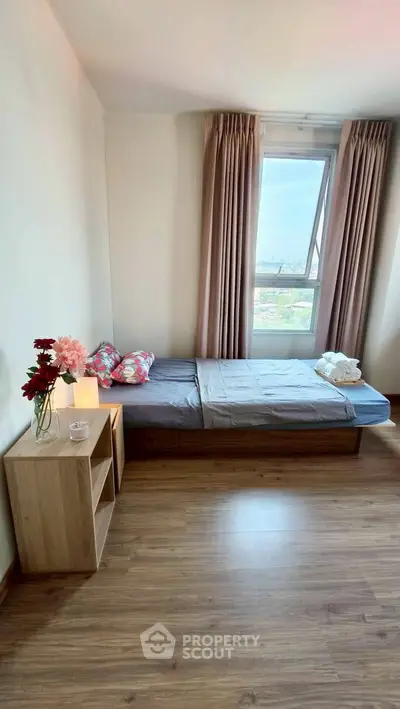 Cozy bedroom with single bed, wooden flooring, and large window with city view.