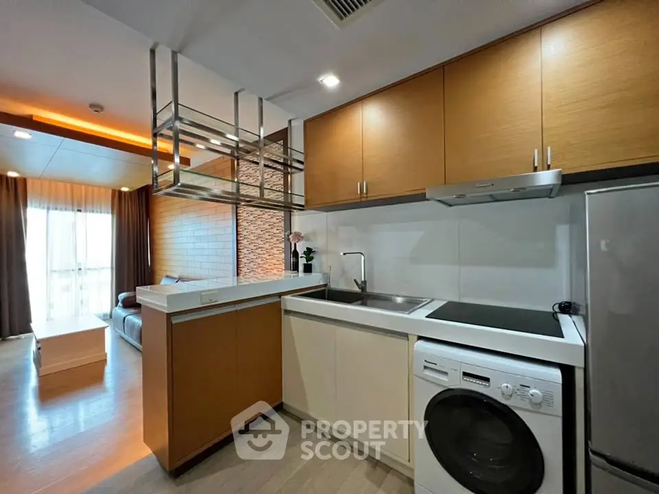 Modern kitchen with integrated washing machine and sleek cabinetry in open-plan apartment.