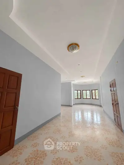 Spacious hallway with elegant tile flooring and wooden doors, perfect for a welcoming entrance.