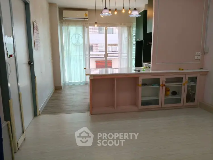 Charming open-layout living space with modern lighting and large windows for natural light.