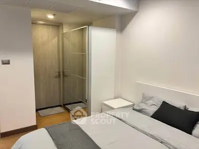 Modern bedroom with minimalist design and neutral tones, featuring a cozy bed and sleek decor.