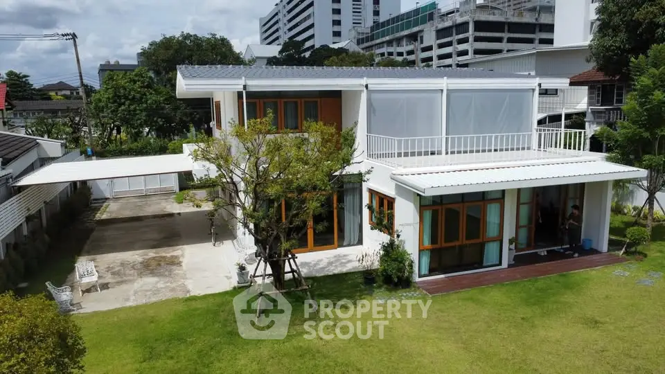 Modern two-story house with spacious garden and large windows in urban setting.
