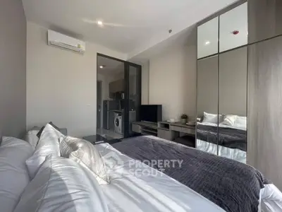 Modern bedroom with mirrored wardrobe and view into kitchen area