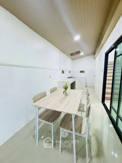 Modern kitchen with sleek dining set and open layout, featuring a minimalist design and natural lighting.