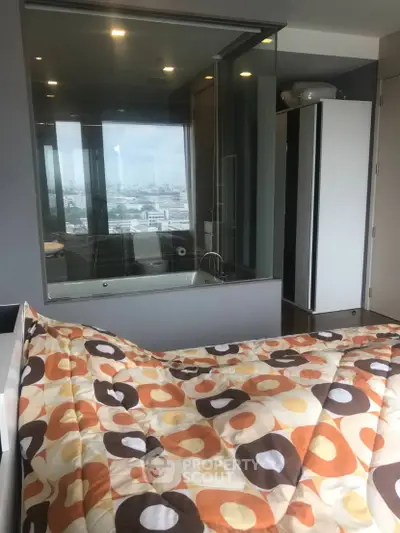 Modern bedroom with city view and glass-walled bathroom, featuring stylish decor and cozy bedding.