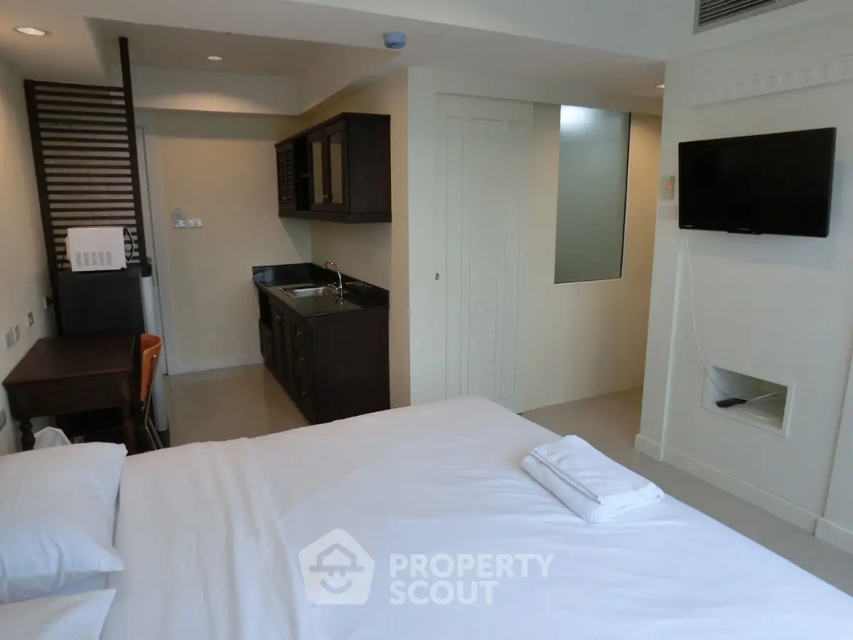 Modern studio apartment with cozy bedroom and compact kitchen area.