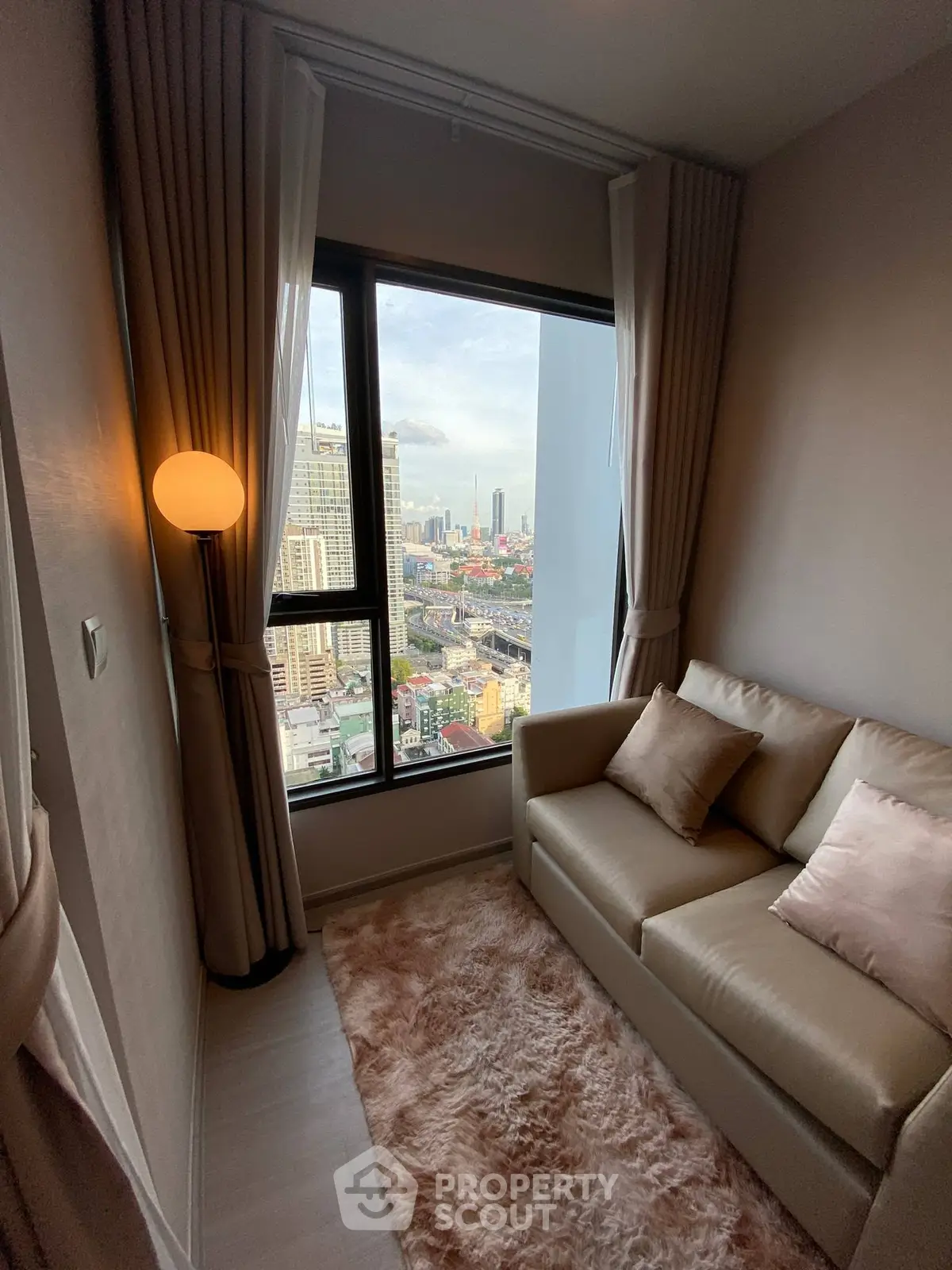 Cozy living room with stunning city view from high-rise apartment window.