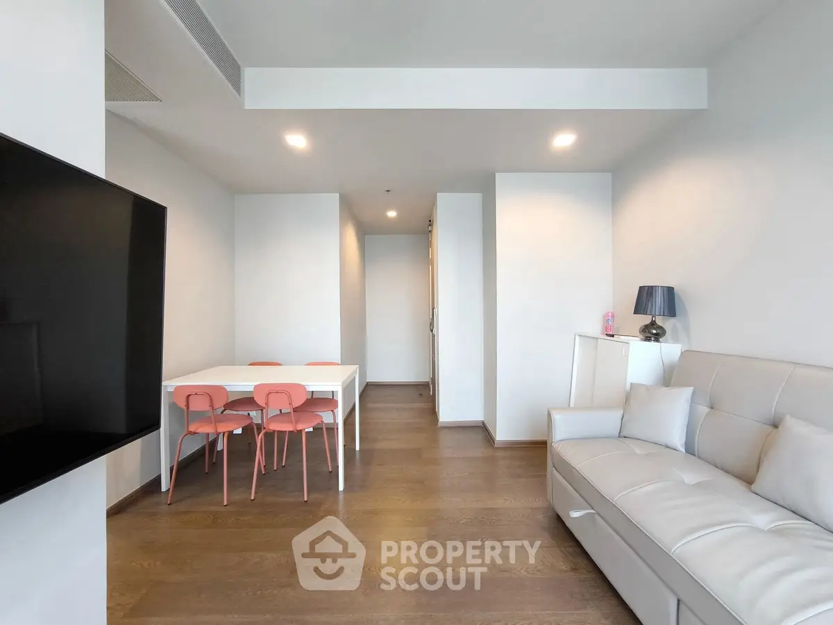 Modern living room with sleek furniture and dining area, featuring a minimalist design and bright lighting.