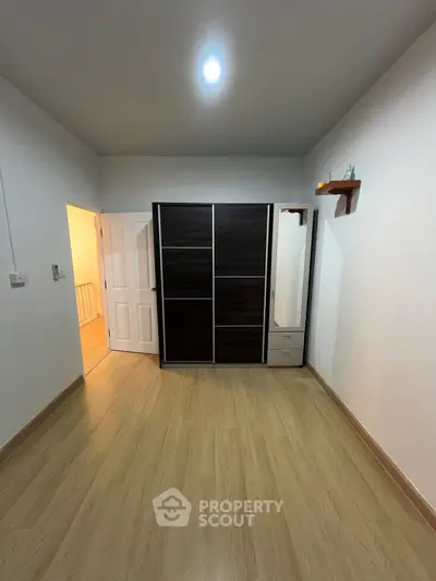 Spacious bedroom with wooden flooring and modern wardrobe design.