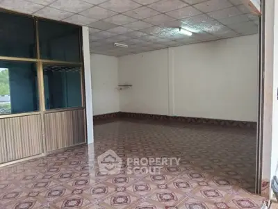 Spacious empty room with tiled floor and large window, ideal for customization.